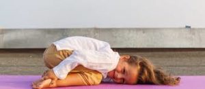 une petite fille en posture de l'enfant bhalasana