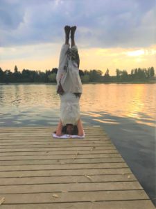 femme en posture sur la tête au bord de l'eau