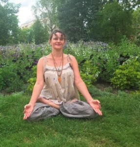 professeure de yoga en posture du lotus dans un jardin