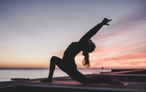 femme en posture de yoga hanuman au bord de la mer au crépuscule