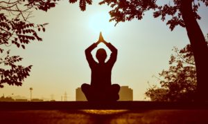 personne assise pratiquant le yoga